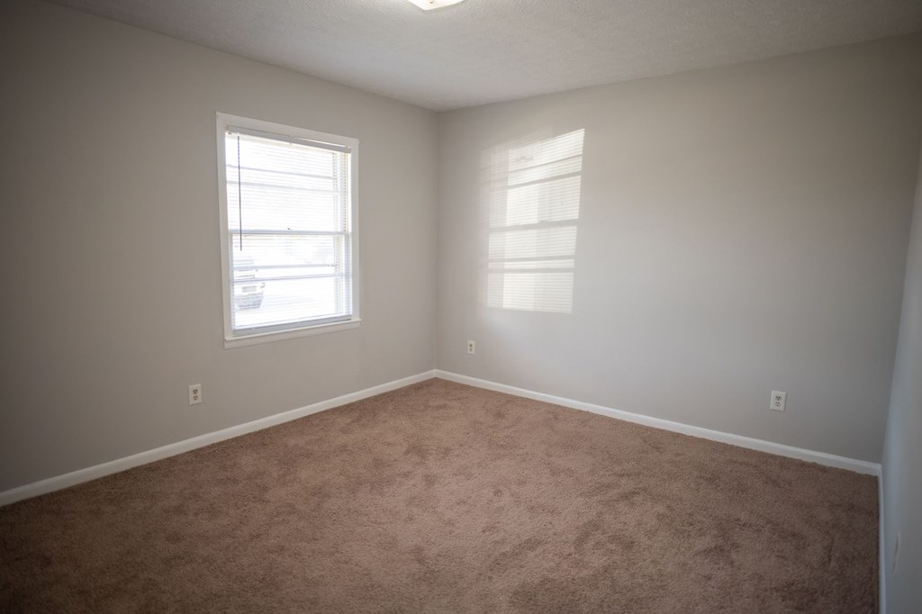A room with a window and carpeted floor.