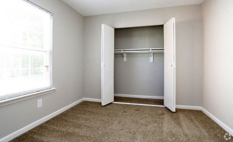 an empty bedroom with a closet and a window