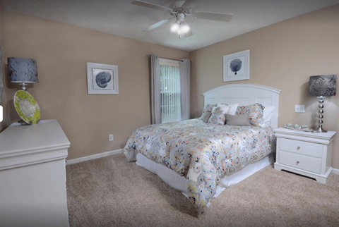 A bedroom with a bed, dresser, and ceiling fan.