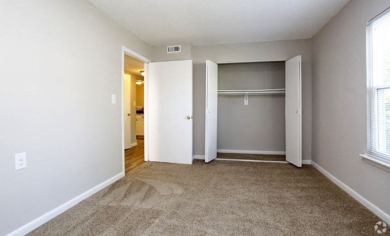 an empty living room with an open door to a closet