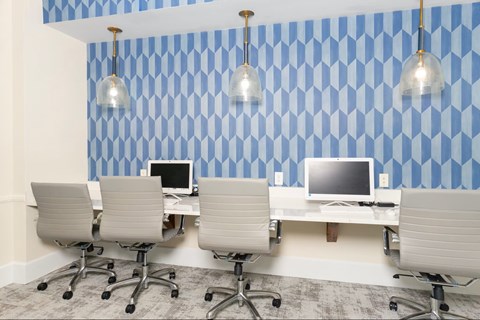 A room with blue and white patterned wallpaper and a row of chairs and desks.
