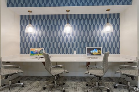 A room with a white desk and four chairs.