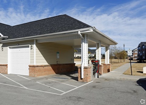 A small building with a white garage door and a covered parking lot.