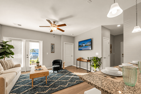 A living room with a ceiling fan and a painting on the wall.