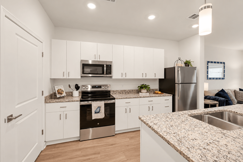 A modern kitchen with white cabinets and stainless steel appliances.