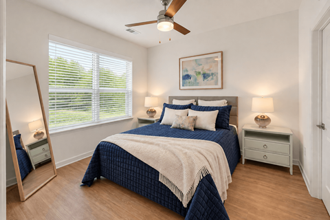 A bedroom with a bed, a dresser, and a ceiling fan.
