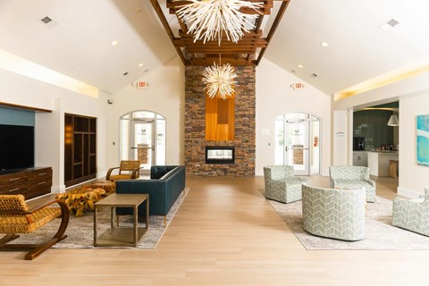 A living room with a stone fireplace and a large chandelier.