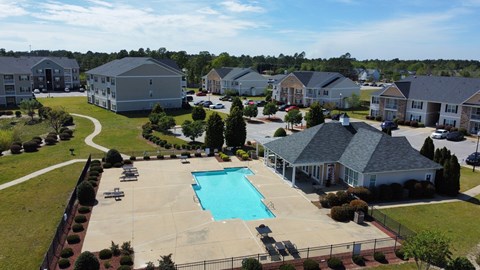 A swimming pool in the middle of a grassy area surrounded by houses.