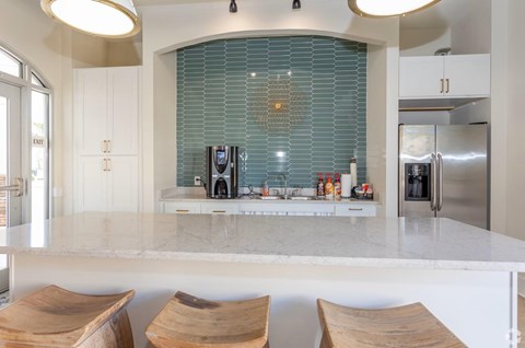 A kitchen with a marble countertop and wooden bar stools.