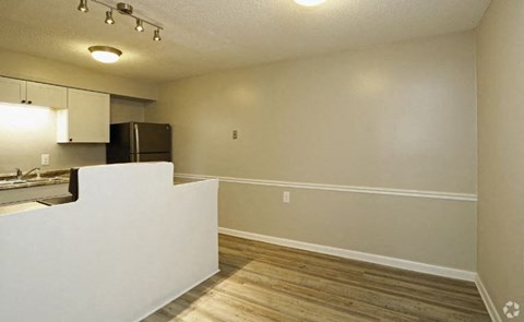 an empty living room and kitchen with a refrigerator