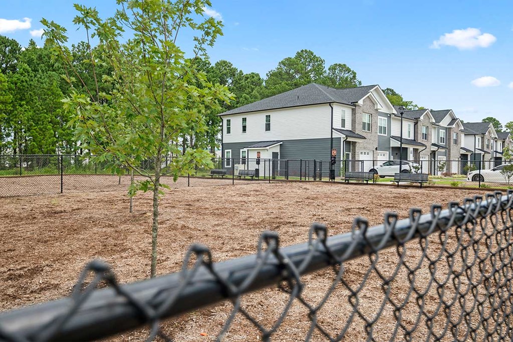 A chain link fence in front of a row of houses.
