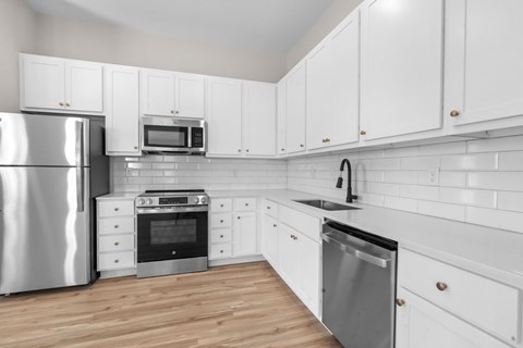 A kitchen with white cabinets and a stainless steel refrigerator.