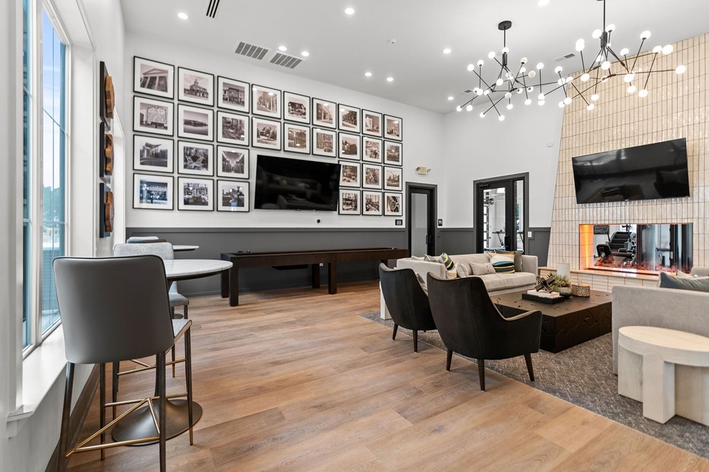 A modern living room with a large TV and a long table with chairs.