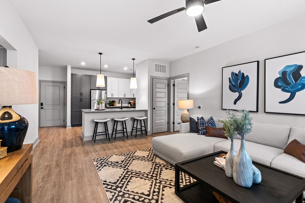 A modern living room with a white sofa, a coffee table, and a ceiling fan.