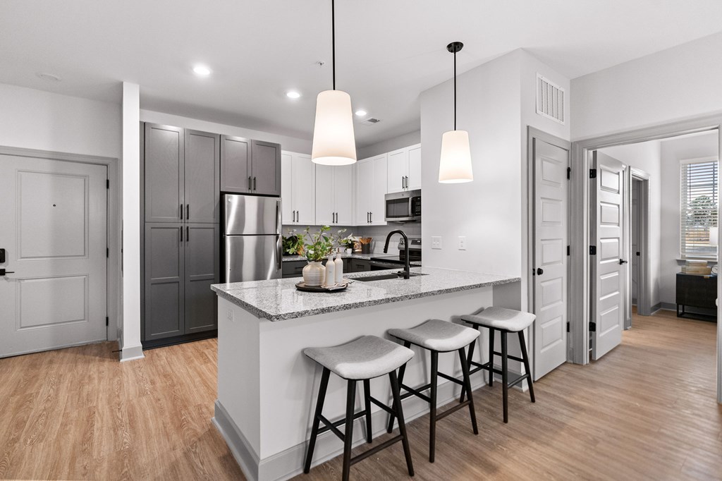 A kitchen with a white countertop and bar stools.
