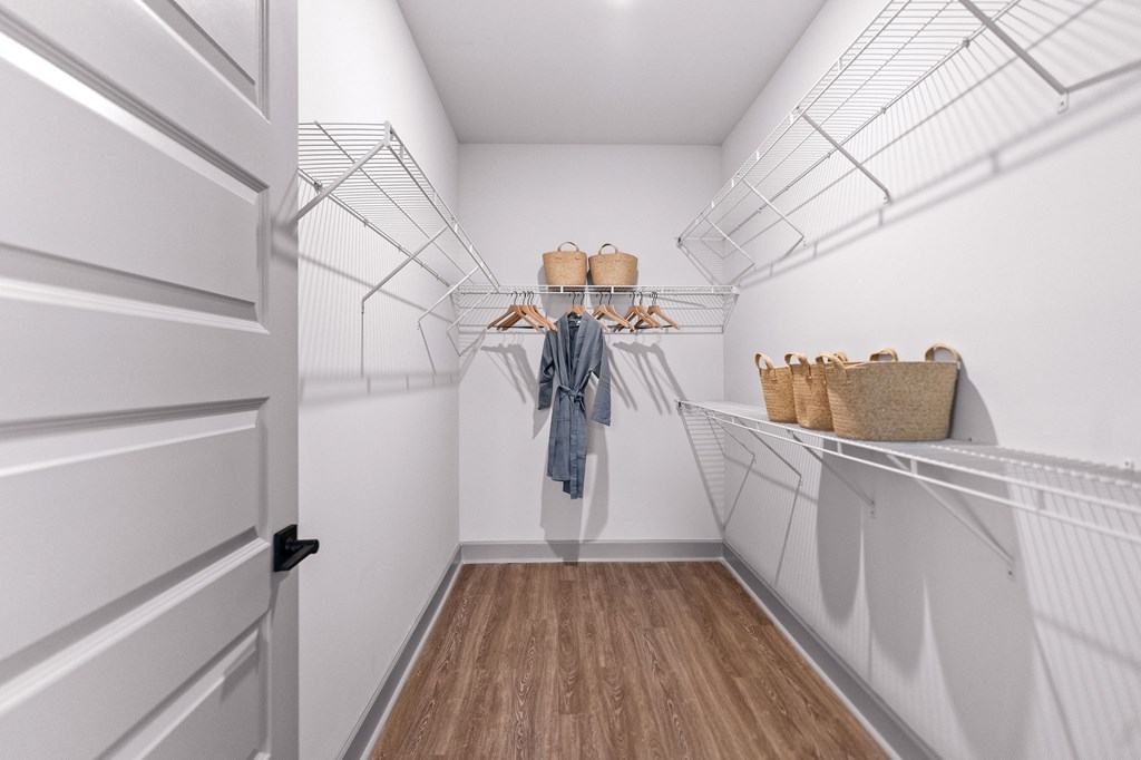 A white closet with a coat hanging on a rod.