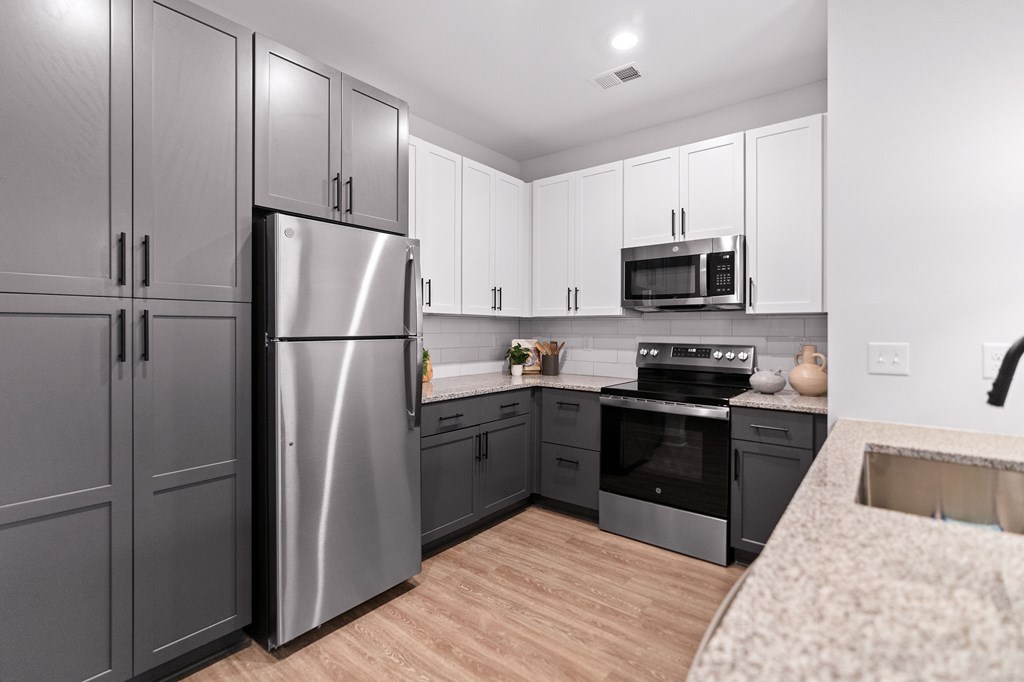 A modern kitchen with a stainless steel refrigerator and microwave above the oven.