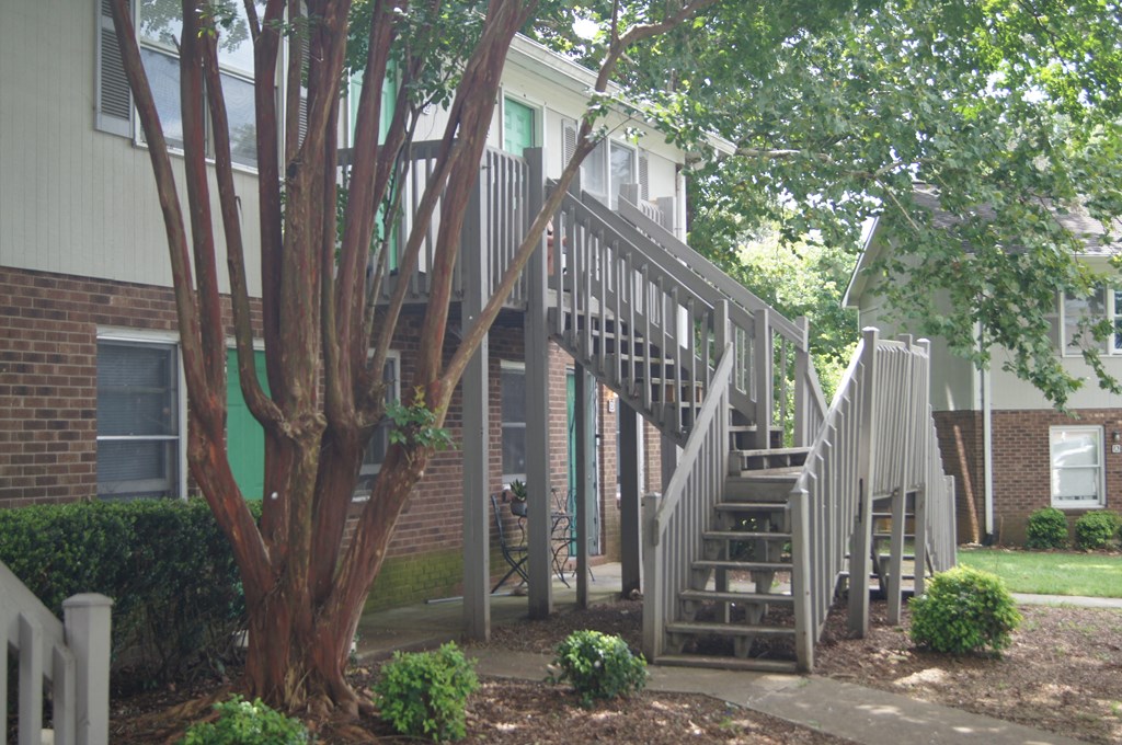 the stairs to the apartment are next to a tree