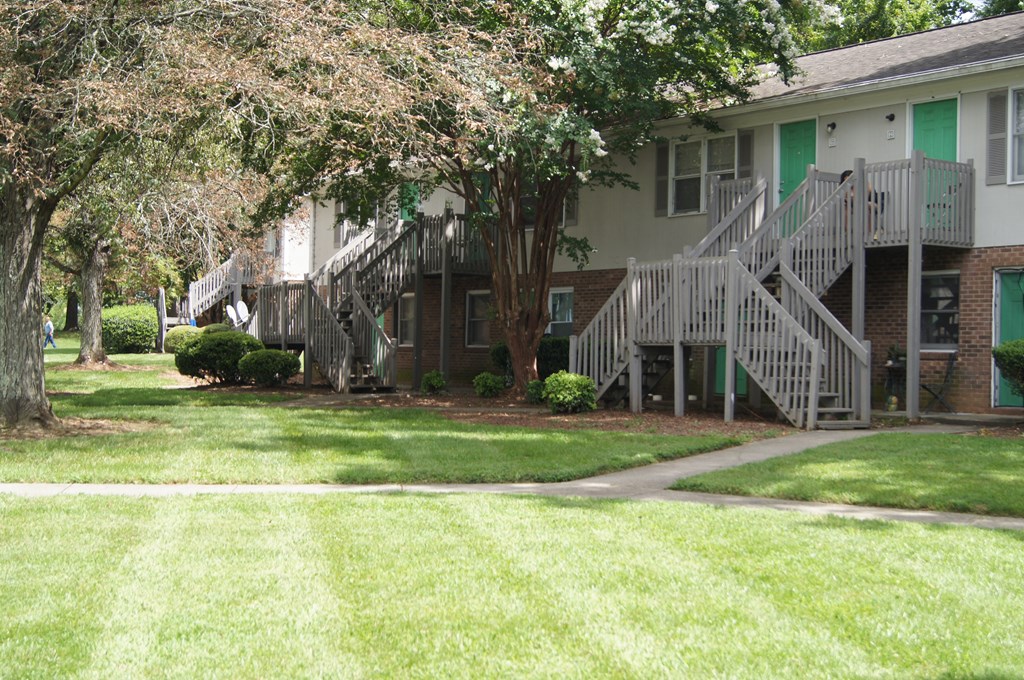 the front of a building with stairs and grass and trees