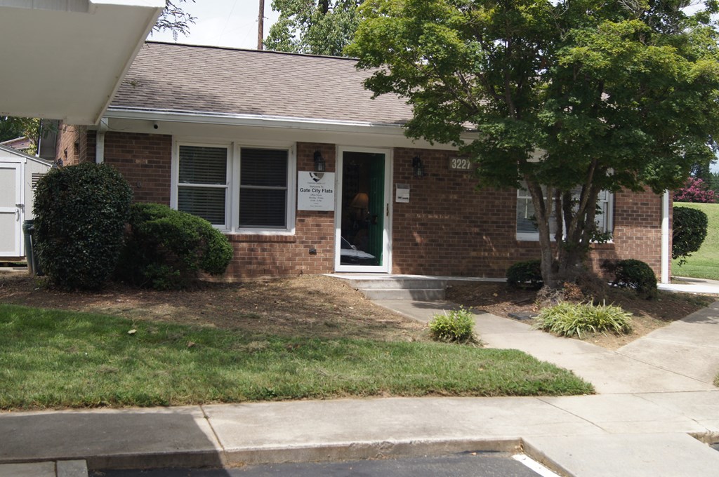 the front of a brick house with a tree in the front yard