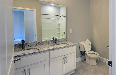 A bathroom with a toilet, sink, and mirror.