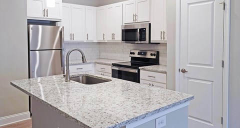 A kitchen with a granite countertop and white cabinets.