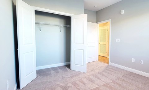 A room with a white door and a carpeted floor.
