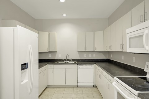 A white kitchen with a refrigerator on the left.