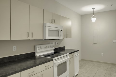 A kitchen with white cabinets and black countertops.