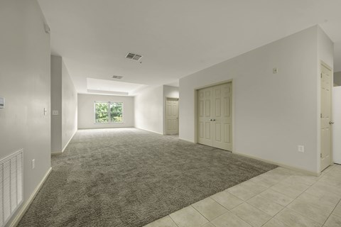 A spacious room with a carpeted floor and tiled walls.
