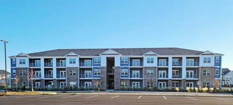 A large apartment building with a parking lot in front.