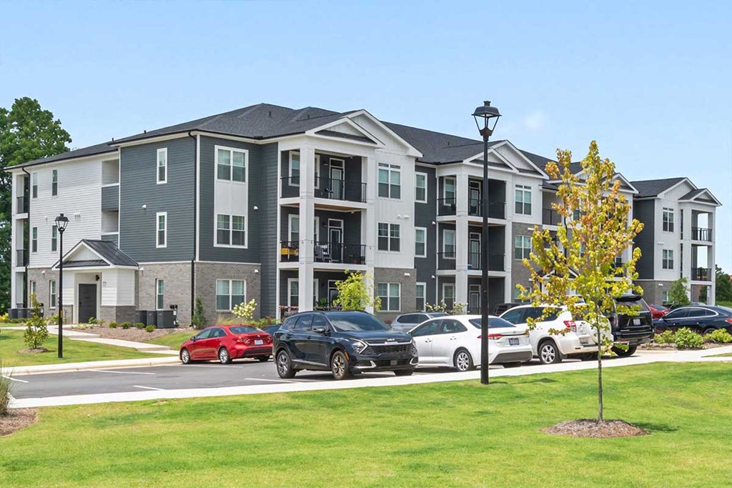 A row of townhouses with cars parked in front.