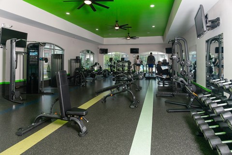A gym with a variety of equipment including treadmills, weights, and exercise machines.