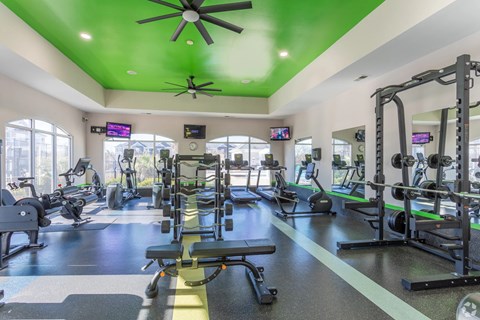 A gym with a variety of equipment including treadmills, weights, and exercise machines.