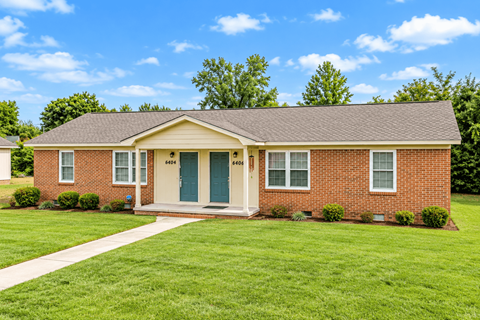 A red brick house with a green door and a small porch.