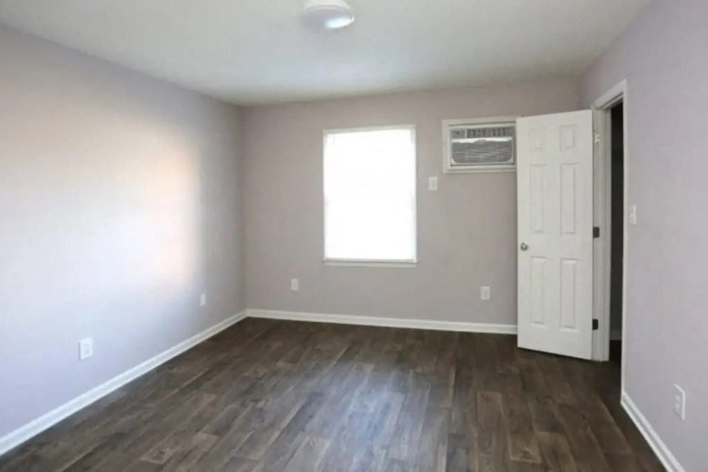an empty living room with wood floors and a white door