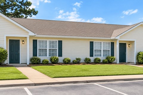 A house with a white siding and green shutters.