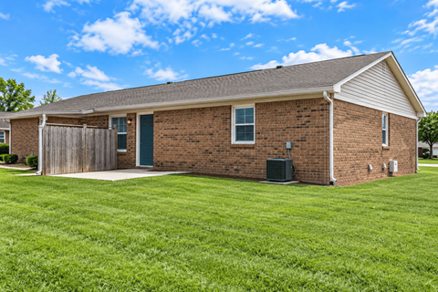 A small brick house with a green door and a wooden fence.