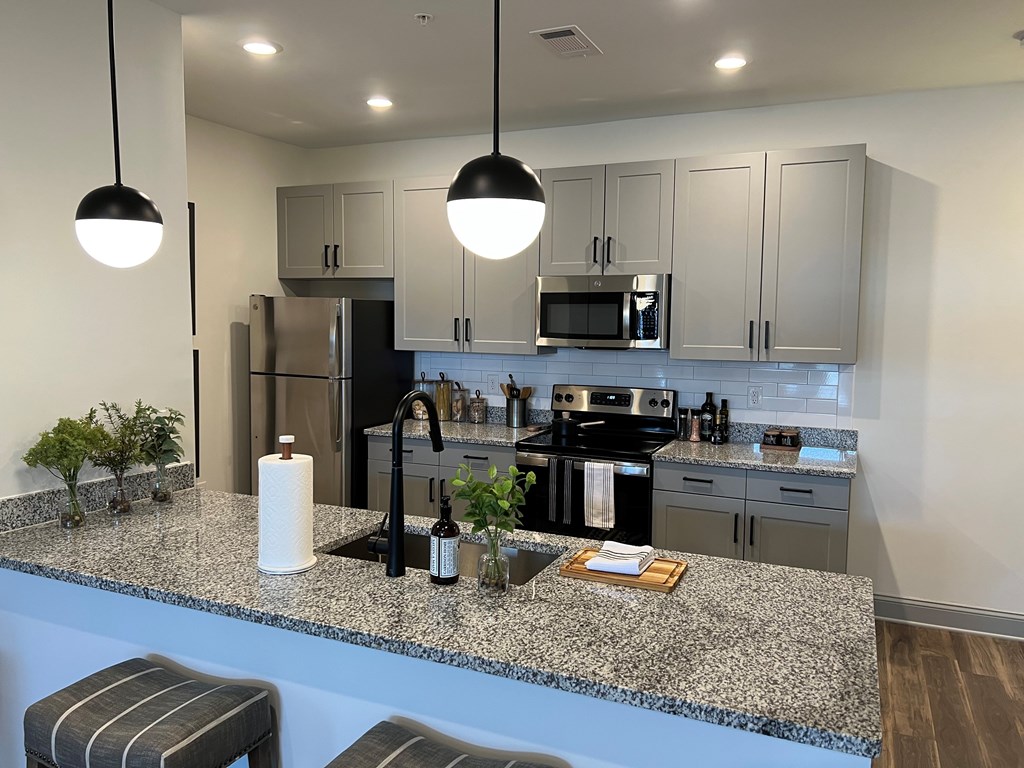 A kitchen with granite countertops and striped bar stools.