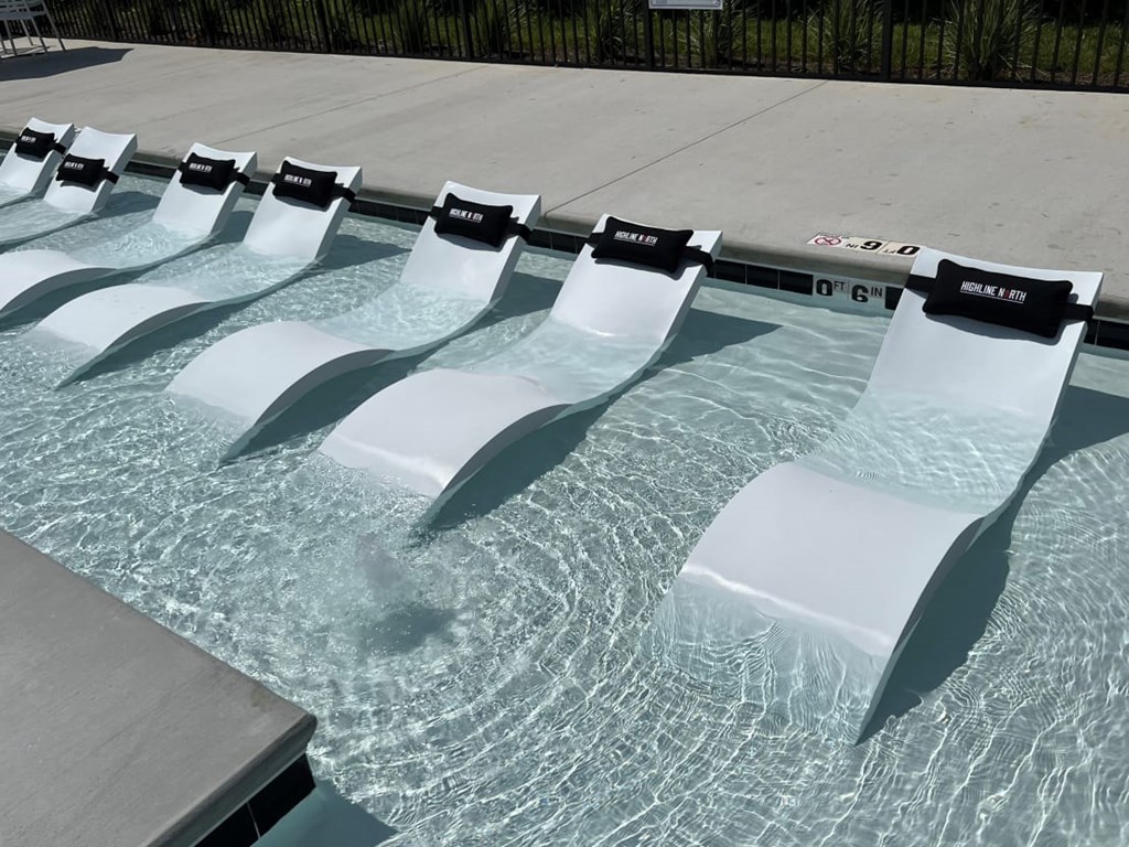 A pool with white diving boards and a black fence in the background.