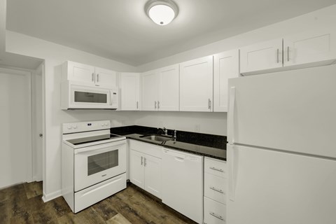 A kitchen with white appliances and cabinets.