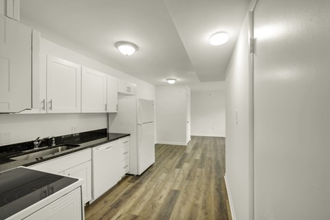A kitchen with white cabinets and a black counter top.