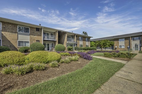 Apartment complex with a well-maintained landscaped garden in front.