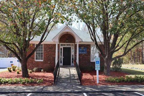 A small brick building with a sign in front of it.