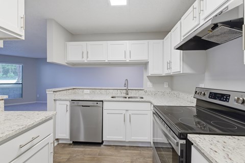 A kitchen with white cabinets and a black stove top oven.
