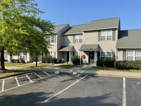 A parking lot in front of a building with a red door.