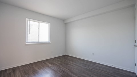 Unfurnished Jefferson Flats bedroom with wood-style flooring and a window.