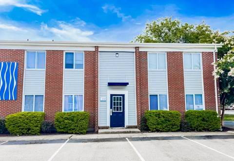 A red brick building with a blue door and windows.