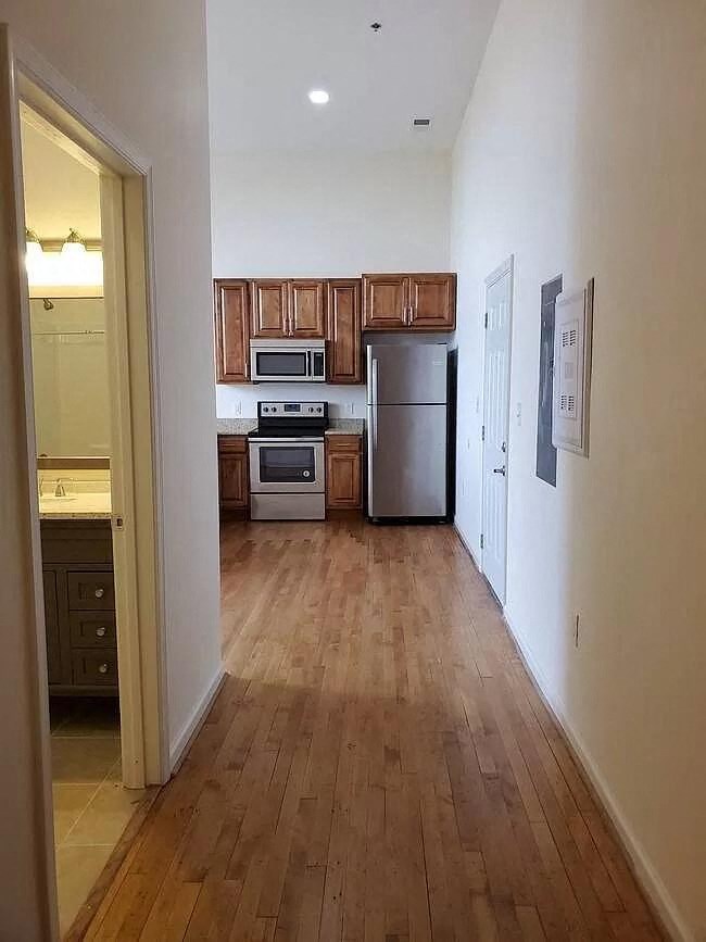 an empty kitchen with wooden floors and stainless steel appliances