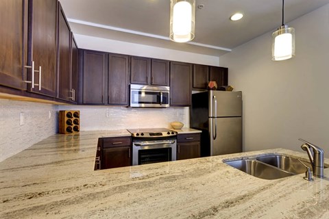 A kitchen with brown cabinets and a granite countertop.